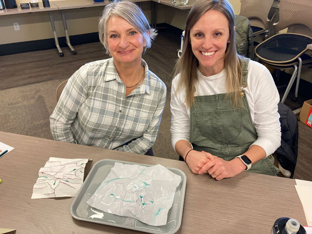 Two teachers with their crumpled paper watershed models