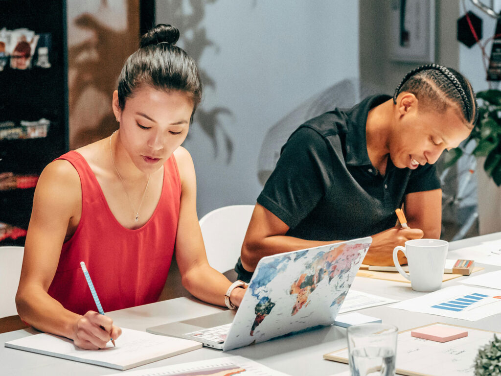 A woman and a man taking notes in a meeting