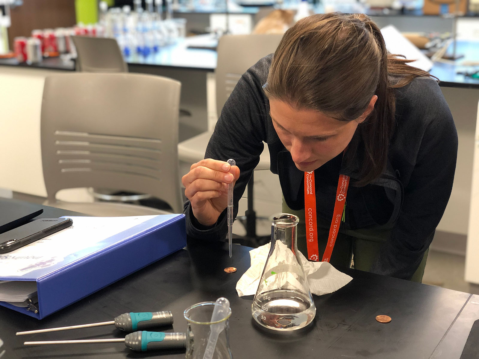 Julia Wilson tests how many drops of water, isopropyl alcohol, and acetone can fit on a penny during an InquirySpace professional development session.